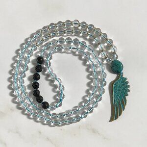 CLEAR QUARTZ AND LAVA MALA WITH A PATINA METAL FEATHER PENDANT